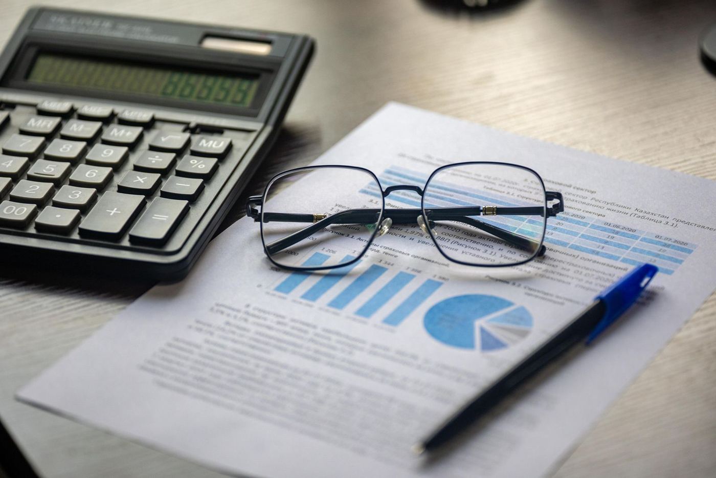 Calculadora, óculos e relatório financeiro sobre a mesa